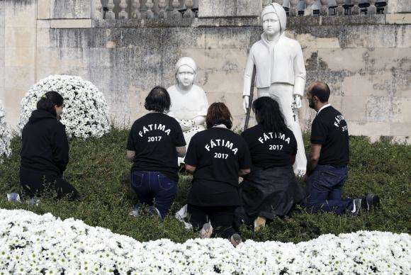 Peregrinos rezam diante das estátuas dos pastorinhos Francisco e Jacinta Marto, no Santuário de Fátima, em Portugal