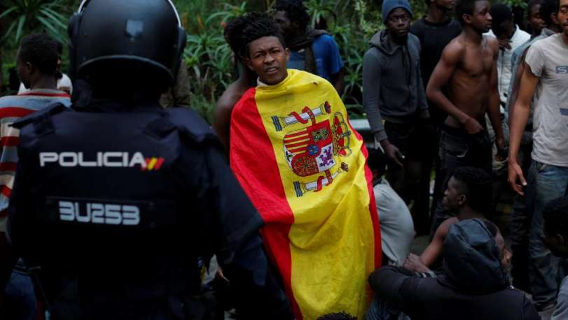 Migrante que cruzou cerca se enrola na bandeira espanhola